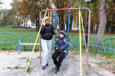 Bir kadın ve oğlu bir sonbahar parkında oyun oynuyorlar..