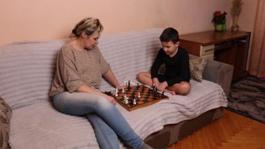 Anne ve oğlu kanepede otururken satranç oynuyorlar..