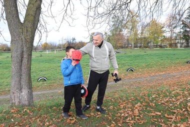 Bir adam ve bir çocuk antrenman eldivenleri üzerinde antrenman yapıyor ve pratik yapıyorlar.