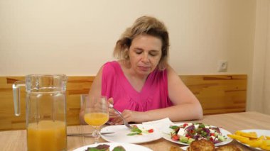 Bir kadın mutfakta masada otururken yiyip içiyor..