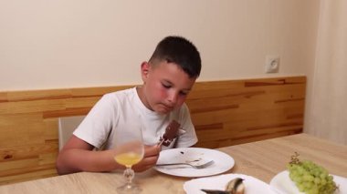 Bir çocuk masada oturuyor ve tatlı olarak dondurma yiyor..