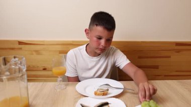 Bir çocuk masada oturuyor ve tatlı olarak dondurma yiyor..