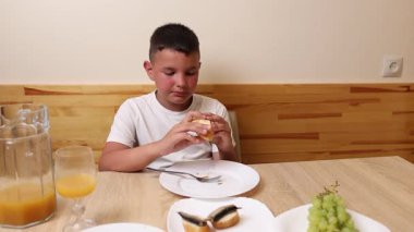 Bir çocuk masada oturuyor ve tatlı olarak dondurma yiyor..