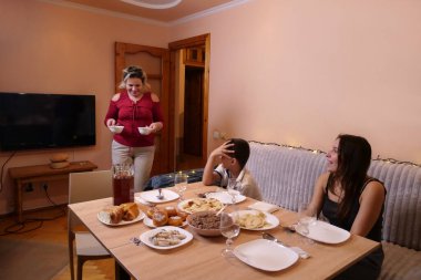 Aile sofrasında sofraya oturur. Bir sürü şenlik yemeği ve Uzvar içkisi..