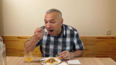 Bir adam mutfakta masada oturuyor, yiyor ve içiyor..