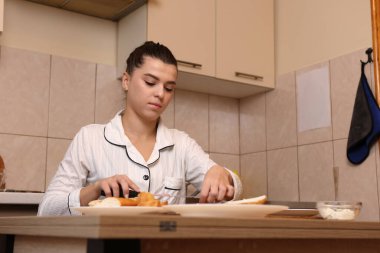 Mutfakta masada otururken güzel genç bir kadın sandviçleri hazırlıyor..