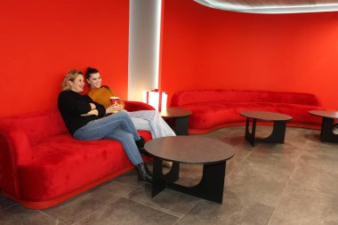 İki kadın kanepede oturmuş film beklerken patlamış mısır yiyorlar..