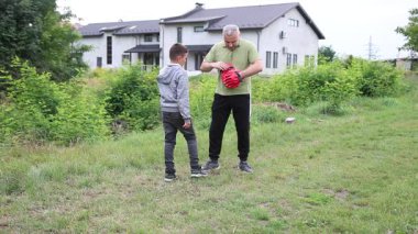 Çocuk, Green Park 'ta yetişkin koçuyla boks antrenmanı yapıyor..