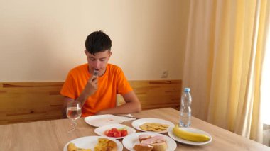 Bir genç masada oturur, su yer ve içer..