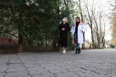 İki kadın sonbahar caddesinde yürüyor, konuşuyor ve gülümsüyor..
