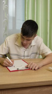 Bir çocuk parlak bir odada masasında kalemlerle çizim yapıyor. Etrafı rahat bir ev atmosferiyle çevriliyken sanat eserlerine odaklanıyor. Dikey video