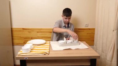 Bir adam mutfakta masada otururken bulaşıkları yıkayıp parlatıyor..