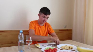 Bir genç masada oturur, su yer ve içer..