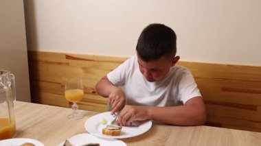 Bir çocuk masada otururken meyve suyu yer ve içer..