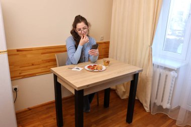 Bir kadın kahvaltıda çay içer ve hamur işi yer..