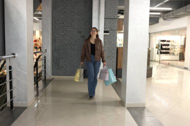 Genç bir kadın alışveriş merkezinde mutlu bir şekilde alışveriş yapıyor..