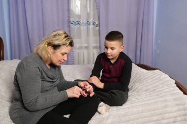 Anne, oğullarının tırnaklarını kesmeye, bakım ve konforunu göstermeye odaklanmış..