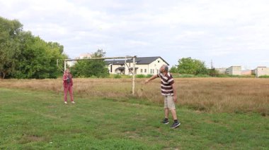 Bir erkek ve bir kadın spor sahasında badminton oynuyorlar, açık havada eğleniyorlar..