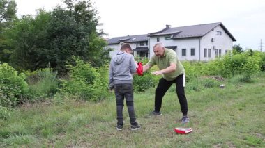Çocuk, Green Park 'ta yetişkin koçuyla boks antrenmanı yapıyor..