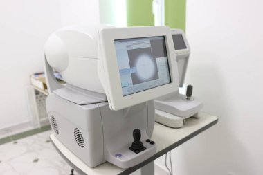 Kırılma hatalarını doğru bir şekilde tespit etmek için otomatik göz ölçümlerinde kullanılan, beyaz klinik bir ortamda monitör, klavye ve fare ile modern otomatik otomatik fraktör..