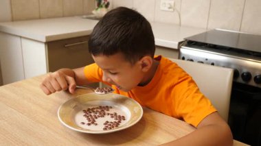 Kahvaltıda tahıl gevreği ve süt yiyen çocuk. Besleyici ve sağlıklı çocuk mamaları..