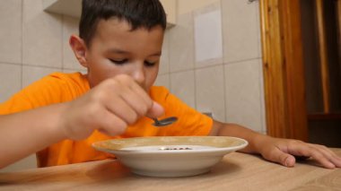 Kahvaltıda tahıl gevreği ve süt yiyen çocuk. Besleyici ve sağlıklı çocuk mamaları..