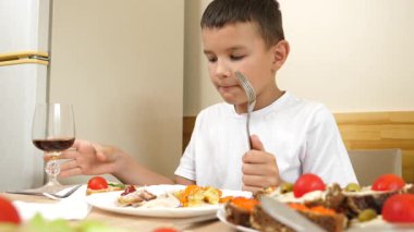 Bir çocuk masada otururken soda yer ve içer..