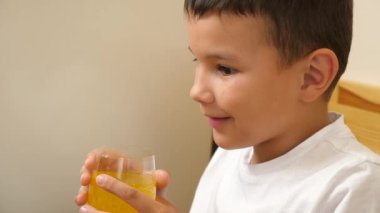 Bir çocuk karbonatlı tatlı su içer ve masada otururken yemek yer..