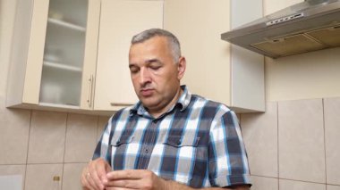 Adam mutfakta çikolata yiyor.