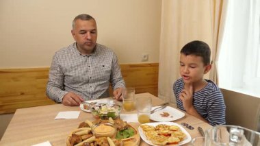 İnsan ve oğul masada otururken meyve suyu yer ve içerler.