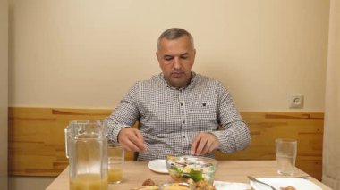 Masada otururken sebze yiyen bir adam. Yakın plan.