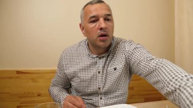 Adam masada otururken çatalla meyve yiyor.