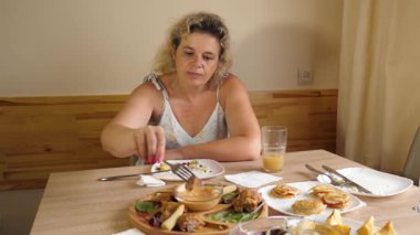 Bir kadın masada otururken et yemeği yer..