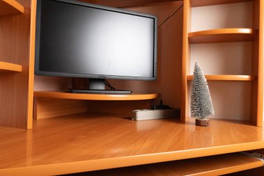 Ev içinde küçük dekoratif Noel ağacı olan ahşap masada bilgisayar monitörü.