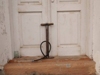 Eski bir verandaya yıpranmış ahşap kapılara karşı hortumlu elle bisiklet pompası.