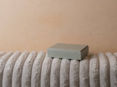 Yumuşak battaniyeye yerleştirilmiş küçük hediye kutusu, depolama için minimalist öge.