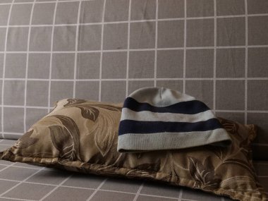 Sakin bir ev ortamında, kanepedeki dekoratif yastığın üzerine örülmüş bir şapka..