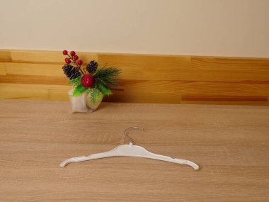 Plastik elbise askısı küçük dekoratif bir tatil öğesinin yanında bir masanın üzerinde duruyor..