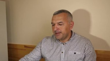 Adam masadaki bardaktan su içiyor, yemeğini bitiriyor.