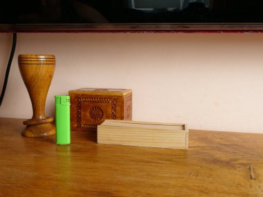 Dekoratif eşyaların yanında, tahta masanın üzerinde duran yeşil plastik çakmak.