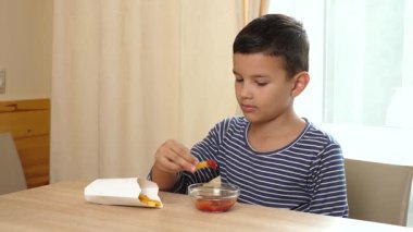 Çocuk evde yemek yerken ketçapla patates kızartması yiyor..