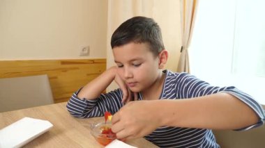 Masada ketçapla patates kızartması yiyen çocuk evde atıştırmaya odaklanmış..