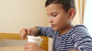 Çocuk evde öğle yemeği yerken yoğurt ya da ekşi krema yiyor..