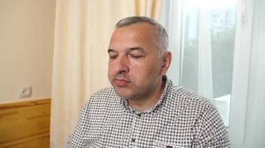 Evdeki masada öğle yemeği yerken çatalla hamur köftesi yiyen bir adam. Yakın plan.