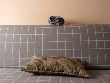 Gri kareli kanepenin arkasında katlanmış çizgili battaniye. Basit bir iç mekan..