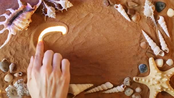 Рука малює символ Сонця в піску. Пляжний фон. Вид зверху — стокове відео