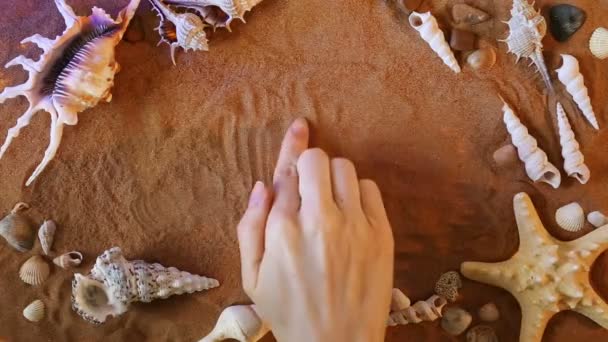 Hand hartsymbool tekening in het zand. Beach achtergrond. Bovenaanzicht — Stockvideo