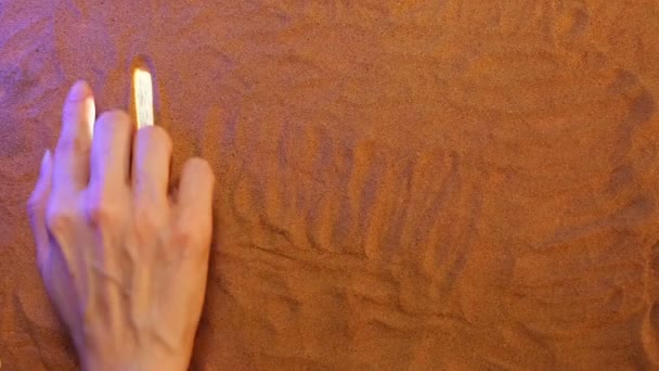 Χέρι σχέδιο Τύνιδα σύμβολο στην άμμο. Παραλία φόντο. Κάτοψη — Αρχείο Βίντεο