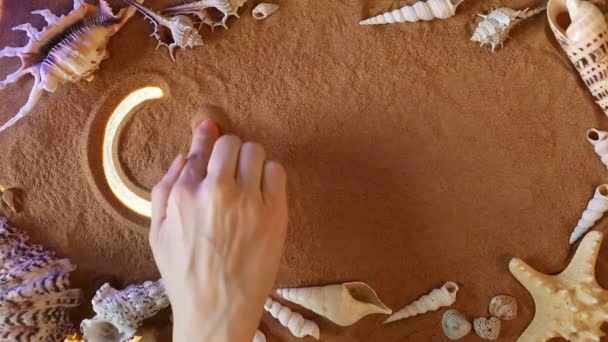 手に砂の中開いているシンボルを描画します。ビーチの背景。トップ ビュー — ストック動画