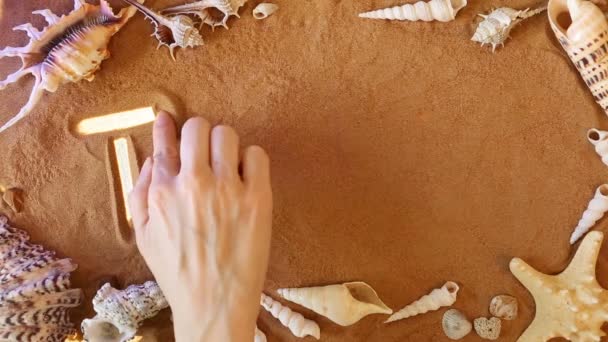手に砂の中旅行シンボルを描画します。ビーチの背景。トップ ビュー — ストック動画